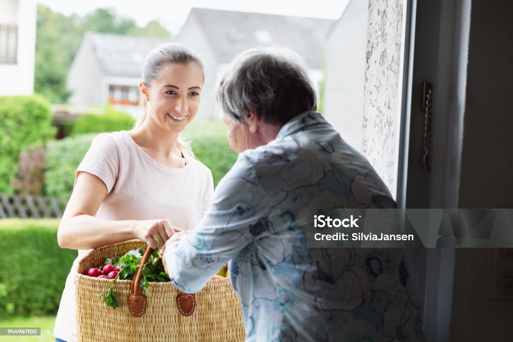 Junge Betreuer liefert Lebensmittel an ältere Frau - Lizenzfrei Freiwilliger Stock-Foto