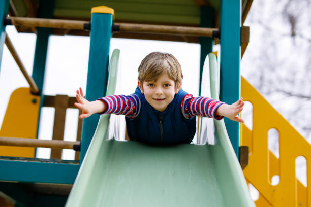 istock Happy blond kid boy having fun and sliding on outdoor playground 944962374