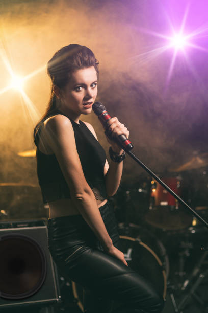 istock Young woman singing on illuminated stage 944965454