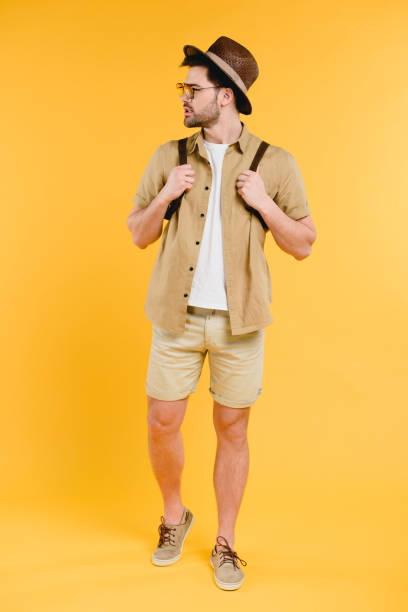 istock handsome young man with backpack looking away isolated on yellow 944975360