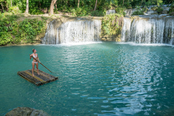 istock Young woman bamboo rafting at tropical waterfall 944978736