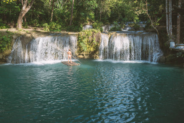 istock Young woman bamboo rafting at tropical waterfall 944979272