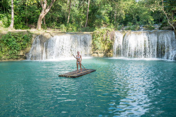 istock Young woman bamboo rafting at tropical waterfall 944980104