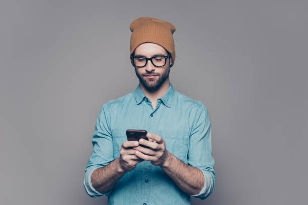 istock Handsome young man in yellow hat and glasses typing sms 944980510