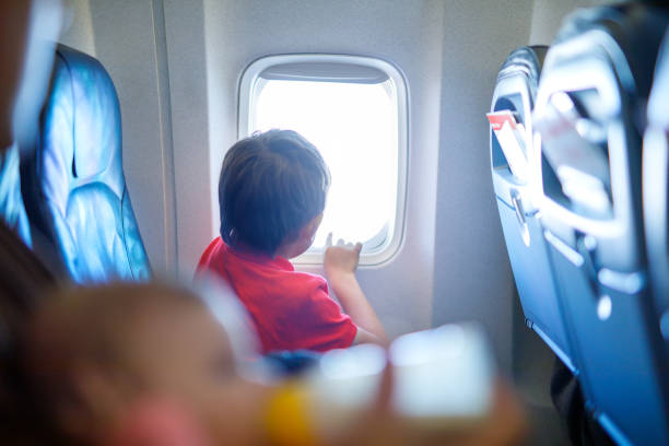 istock Little kid boy looking outside of plane window during flight on airplane. 944982684