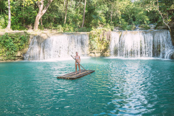 istock Young woman bamboo rafting at tropical waterfall 944982736