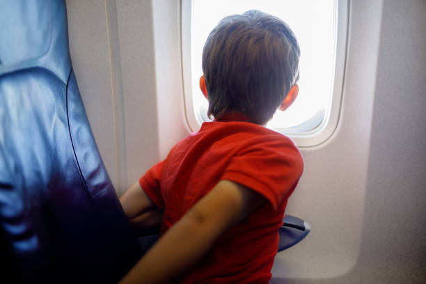 istock Little kid boy looking outside of plane window during flight on airplane. 944982824
