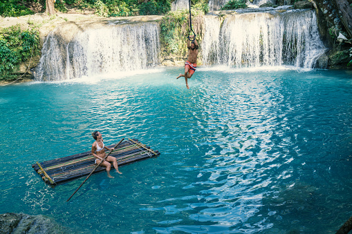 Young couple having fun at a beautiful waterfall on Siquijor Island in the Philippines. People travel nature adventure concept. Two people romance love sharing enjoying outdoors and tranquillity in a peaceful environment, traveler concept