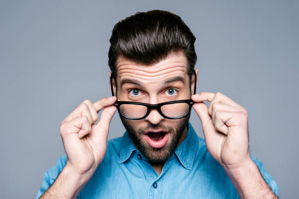 istock Wow! Surprised young man with opened mouth touching glasses 944983130