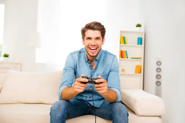 Photo of Portrait of excited happy cheerful man playing video game