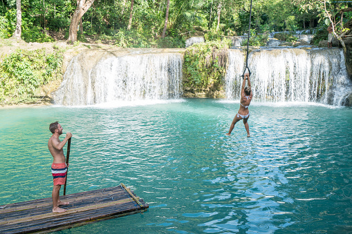 Young couple having fun at a beautiful waterfall on Siquijor Island in the Philippines. People travel nature adventure concept. Two people romance love sharing enjoying outdoors and tranquillity in a peaceful environment, traveler concept