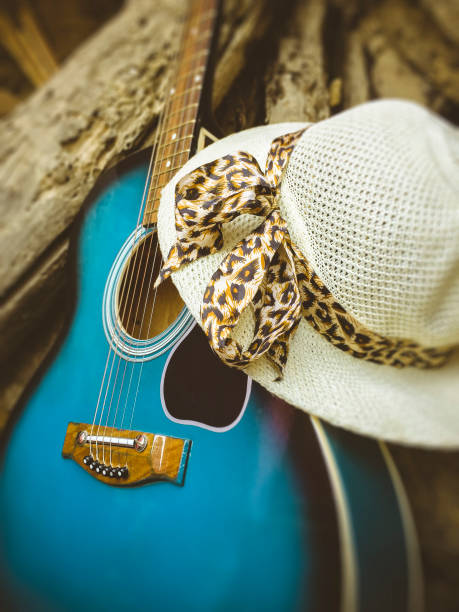 istock Acoustic guitar with lady's hat in rustic wooden background. 944983890