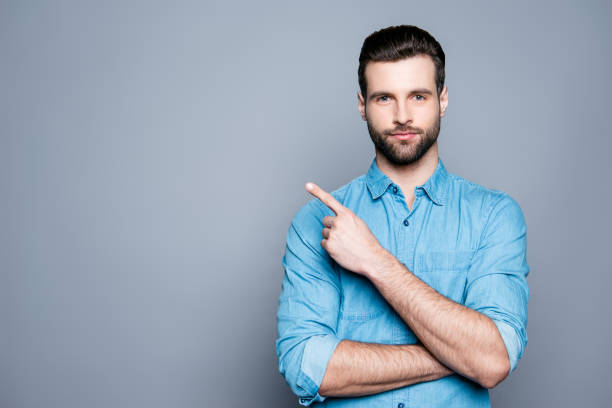 istock Handsome smiling bearded man pointing away on gray background 944986568