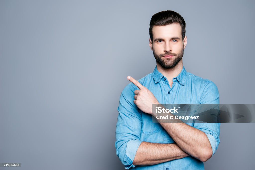 Sorriso bonito barbudo homem apontando para fora em fundo cinza - Foto de stock de Homens royalty-free