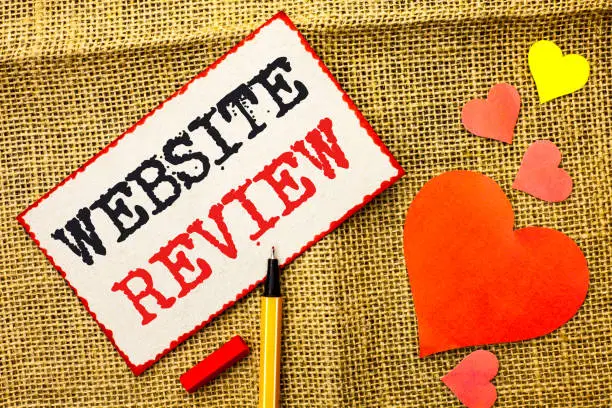 Photo of Handwriting text Website Review. Concept meaning Homepage Evaluation Customer Opinion Satisfaction Ranking written on Sticky Note Paper by Pointer on the jute background Love Hearts next to it.