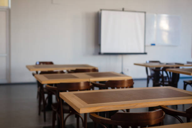 istock Inside the old classroom with blackboard, desks and chairs. 944986622