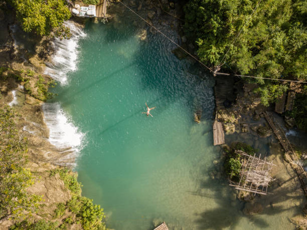 istock Young woman floating in star shape at waterfall in rainforest 944990620