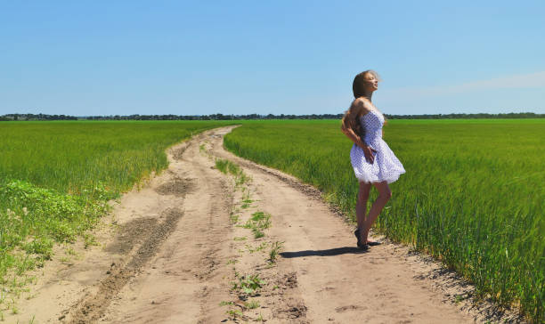 istock On the road among fields is a young girl 944990846