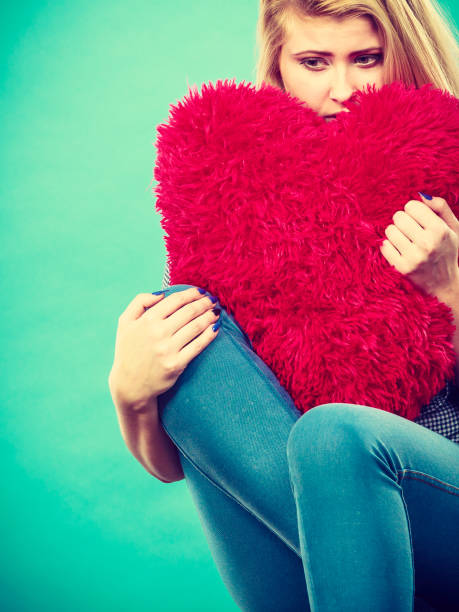 istock Sad woman holding red pillow in heart shape 945001948