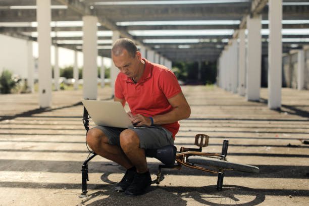 homme implantation sur la moto et l’utilisation d’ordinateur portable - bmx flatland photos et images de collection