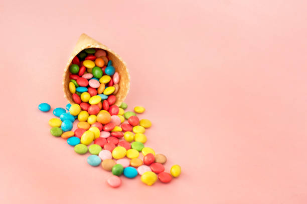 istock Multicolored lollipops in waffle cone on pink background 945009216