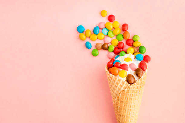 istock Ice cream in a waffle cone with colored candy toppings on a pink background 945009280
