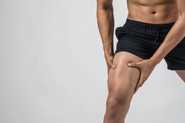 young sport homme avec jambes athlétiques fortes tenant le genou avec ses mains dans la douleur après avoir subi la lésion ligamentaire isolée sur blanc. - cuisse photos et images de collection