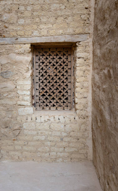 istock Ancient wooden window with geometrical pattern based on the christian cross on external brick stone wall 945017080
