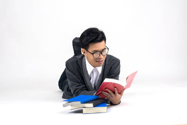 istock Playful happy young man funny round glasses lying with book over white background 945017800