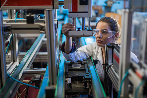 Female engineer examining machine part on a production line.