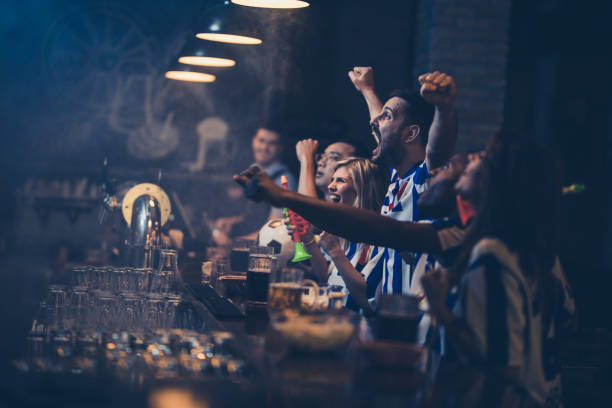 istock Happy soccer fans cheering while watching a game in a bar. 945026012