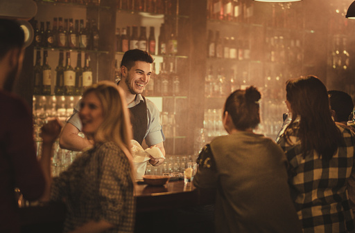 Bartender feliz hablando con sus clientes en un bar. photo