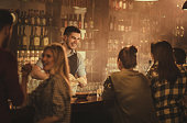 Happy bartender talking to his customers in a pub.