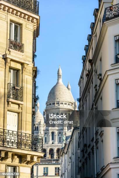 View Of The Facade And Dome Of The Basilica Of The Sacred Heart In Paris Through A Narrow Street Between Typical Buildings Under A Clear Blue Sky Stock Photo - Download Image Now