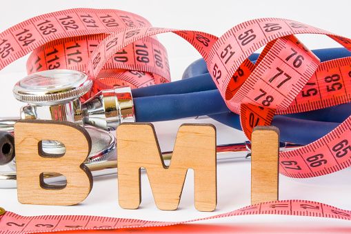 BMI or body mass index abbreviation or acronym photo concept in medical diagnostics or nutrition, diet. Word BMI is on background of tape to measure the circumference of body and medical stethoscope
