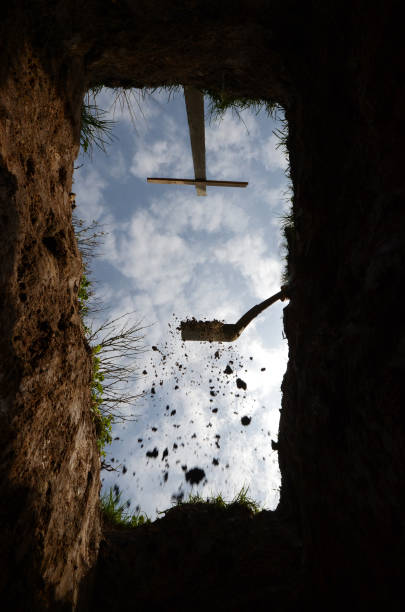 The very last view from the grave View upwards from the botom of a grave, a last glimpse of the sky. The gravedigger has begun covering the grave. grave digger stock pictures, royalty-free photos & images