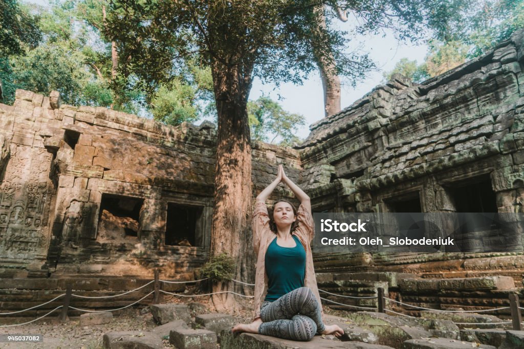 Woman doing yoga in  Ta Prohm temple Young Caucasian woman doing yoga in Ta Prohm temple of Angkor, Siem Reap, Cambodia Yoga Stock Photo