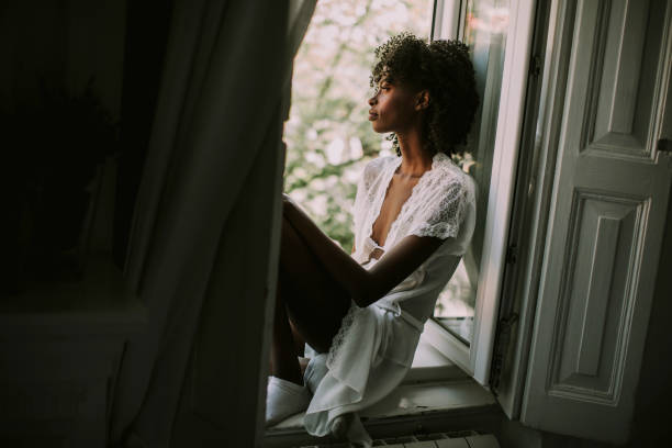 istock Pretty young black woman sitting on the window 945037278