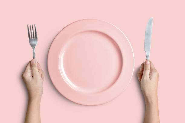 placa de color rosa con plata tenedor y cuchillo en fondo rosa - empty fork fotografías e imágenes de stock