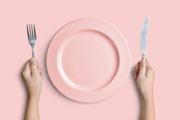 assiette rose avec argent fourchettes et des couteaux sur fond rose - plate silverware table white photos et images de collection