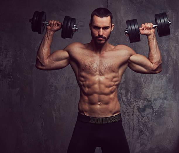 istock Brutal athletic bearded shirtless male doing exercise with dumbb 945046384