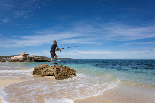 A young man fishing at Hamelin Bay, a popular travel destination and beautiful location.