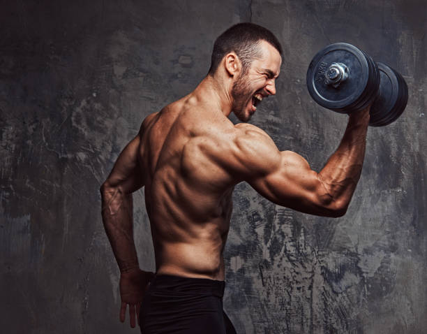 istock Brutal athletic bearded shirtless male doing exercise with dumbb 945048710
