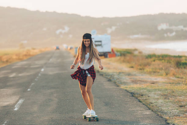 istock Beautiful girl with longboard skating on road 945052452