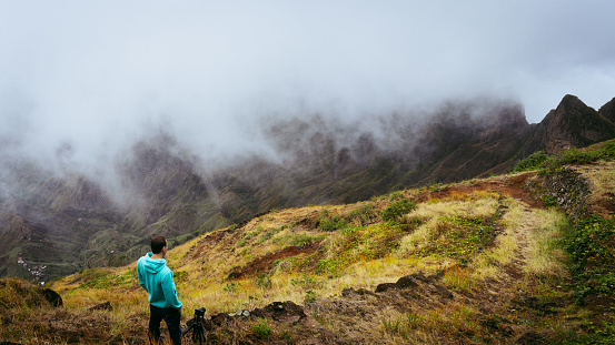 Panoramic shot of traveler taking picture of amazing steep mountain range and terrain canyon valley on the path from Xo-Xo Valley. Camera on tripod.Santo Antao Island, Cape Verde.
