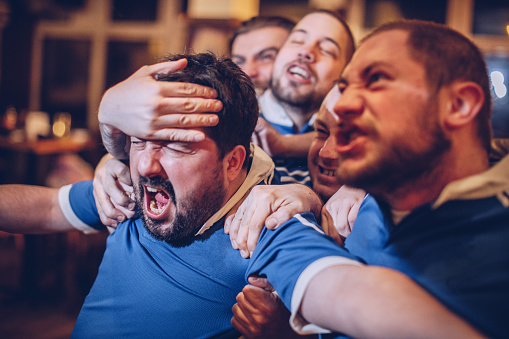 Group of men watching game in sports pub