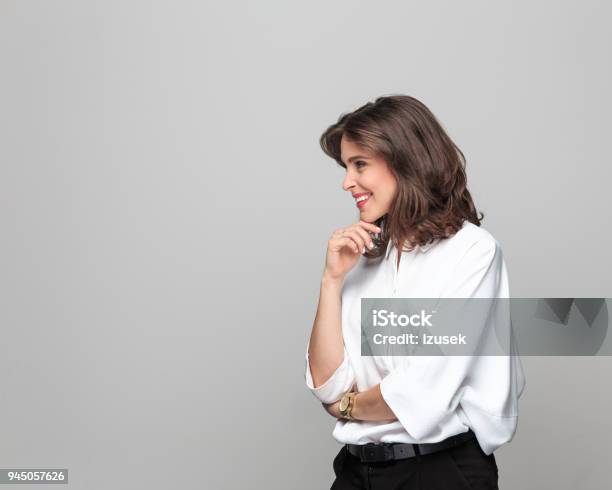 Side View Of Beautiful Young Businesswoman Against Grey Background Stock Photo - Download Image Now