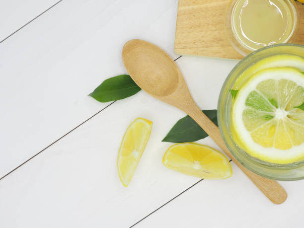 istock Fresh lemon in water, lemonade and lemon slice on white wood background 945057796