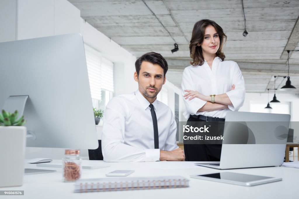Two business partners in office Two business partners working together in office. Confident young businessman and businesswoman looking at camera. 20-29 Years Stock Photo