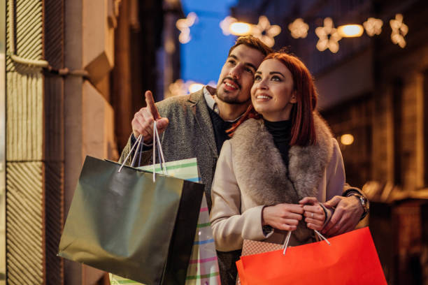 Romantic couple pointing finger at shop item Happy couple standing on the street looking at the shop and pointing finger at something high street shops stock pictures, royalty-free photos & images